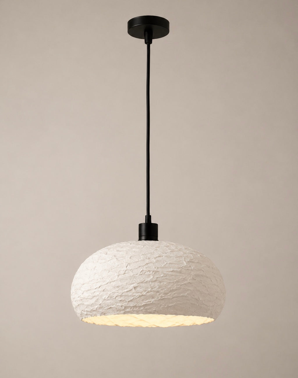A textured white wide-dome pendant light with a matte black cord and canopy, shown against a soft neutral background